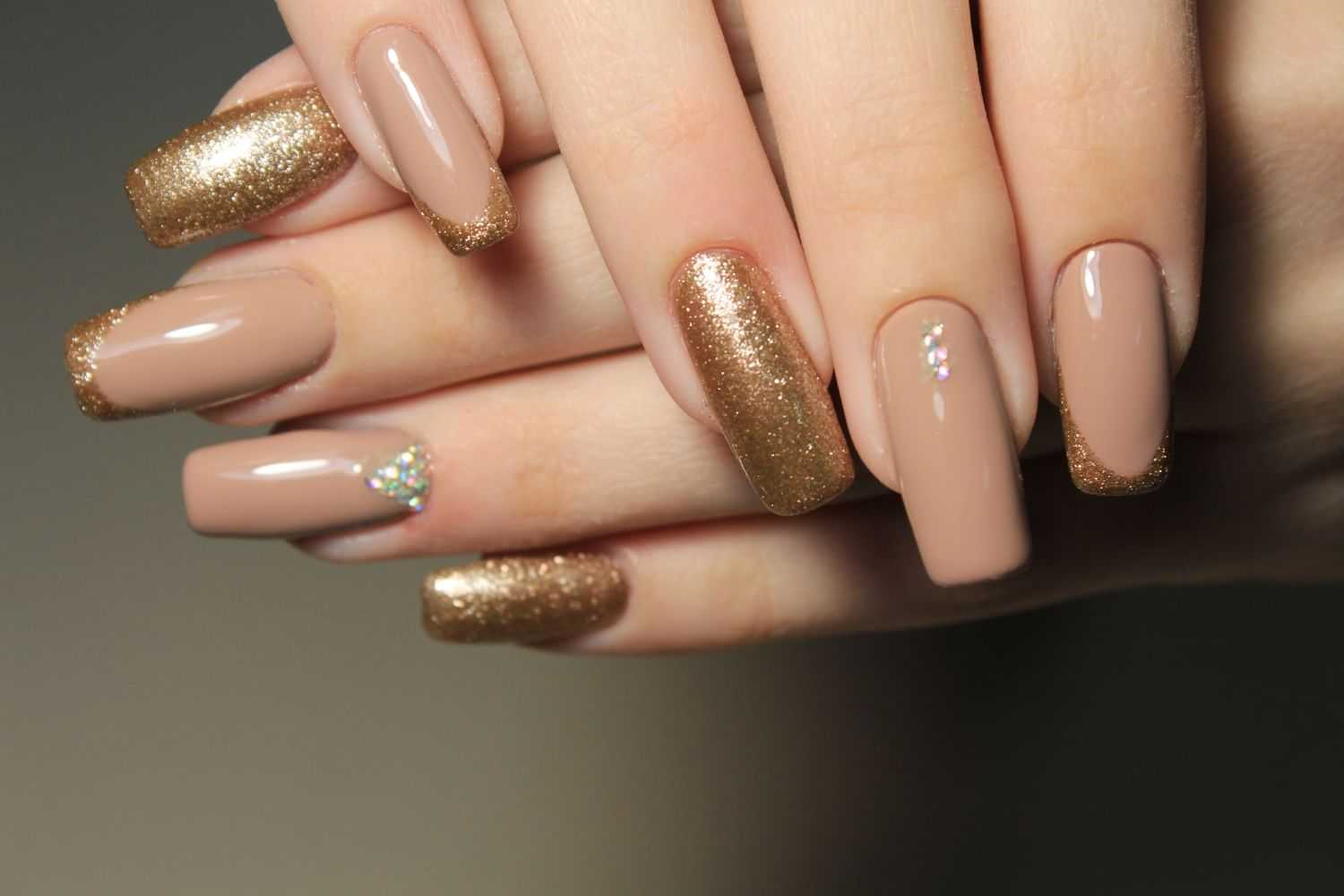 Elegant nude and gold glitter manicure with accent nail design.