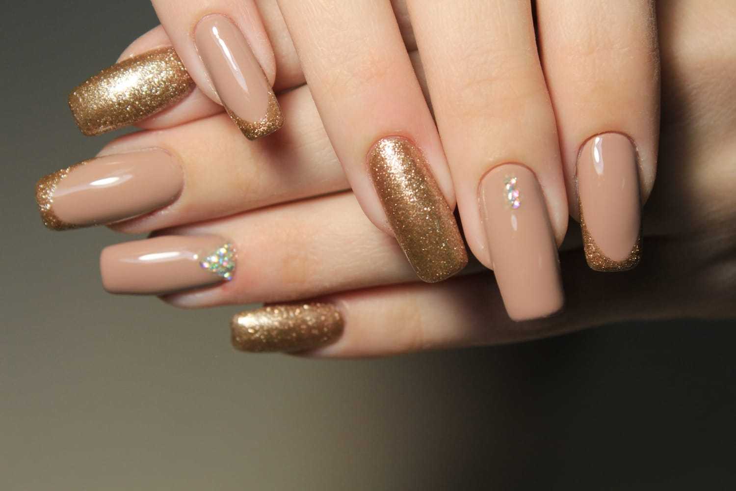 Elegant nude and gold glitter manicure with accent nail design.
